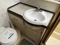 A compact bathroom area featuring a round sink with a faucet and a toilet beside it in a 2000 Ford Motorhome