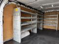 Interior of a 2018 GMC Savana featuring metal shelving units along the walls for storage