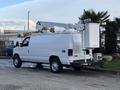 A white 2007 Ford Econoline van with a raised bucket lift attached to the roof and equipment mounted on the rear
