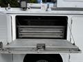 A 2016 Ford F-550 service vehicle with an open compartment featuring metal shelves and a fold-down door