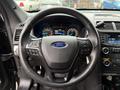 The steering wheel of a 2019 Ford Explorer with controls for audio and cruise features visible on the left side and a blue Ford emblem in the center