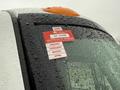 A red certificate of approval sticker is affixed to the window of a 2014 International TerraStar covered in droplets of water