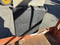 A black briefcase with a handle and some visible wear sits on a metal platform, featuring a blank area for labeling and a few orange markings on its surface