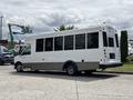A 2020 Chevrolet Express bus with a white exterior and large windows is parked with its rear facing the viewer