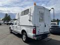 A white 2014 Ford F-350 SD with a custom camper shell mounted on the truck bed and a yellow light on top