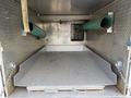 A metallic truck bed of a 2008 Ford F-450 with a textured surface two green pipes extending from the sides and a compartment at the back