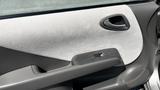 A close-up view of the interior door panel of a 2006 Honda Fit featuring fabric and plastic materials with the door handle and window control button visible