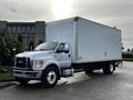 A 2022 Ford F-750 truck with a large white cargo box is parked on a paved surface with its front facing the viewer