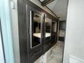 A modern interior of a 2021 Grand Design Recreational 311BHS featuring a wall of mirrored cabinets and a bed area in a compact living space