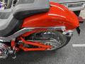 A red 2024 Harley Davidson Fat Boy showing chrome details and a sleek design, highlighting the rear section with a visible wheel and distinctive frame elements