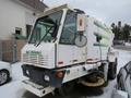 A 2015 Global Street Sweeper with a white body and green stripes featuring large front windows and a rotating brush at the front