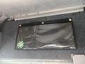 A 2012 Ford Econoline interior detail showing a black organizer with a clear front and circular green emblem on the left side.