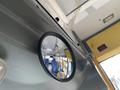 A round mirror mounted on a wall reflecting the interior of a vehicle with blue seats and yellow accents