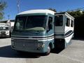 A 2000 Ford Motorhome with a teal and white exterior features a slide-out section on the right side and front windows showcasing its driving area
