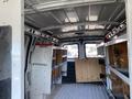 Interior of a 2012 GMC Savana showing shelving and storage compartments along the sides with a wooden panel on the back wall