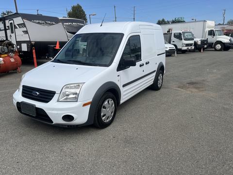 A white 2010 Ford Transit Connect van with a distinctive front grille and rounded headlights parked in a lot
