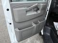 The interior side of a 2016 GMC Savana door with a gray panel featuring a door handle and cup holder compartment