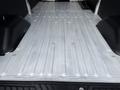 A 2022 Ford Transit cargo area showing a flat, metallic floor with ridges and two black wheel wells on either side