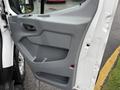 The interior side of a 2018 Ford Transit van's door showing a gray plastic panel with a handle and storage compartment