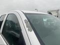 A 2015 GMC Sierra 1500 with a damaged paint section on the windshield frame and raindrops on the glass