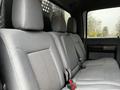 The interior of a 2014 Ford F-550 featuring a grey upholstered backseat with a split design and seat belts visible