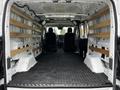A 2023 Ford Transit van with an empty cargo area featuring wooden shelving and black rubber flooring