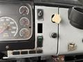 The interior dashboard of a 2003 Freightliner FL70 featuring gauges for speed fuel and other indicators along with various switches and controls