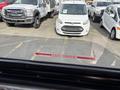 A 2018 Chevrolet Express van parked in a row of vehicles including a white Ford van and a smaller white car