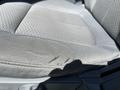 A close-up of a gray fabric seat in a 2014 Ford F-150 showing noticeable wear and a tear in the material