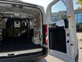 A 2023 Ford Transit van with its rear doors open showcasing an empty cargo area featuring wood paneling and a partition with a metal grille