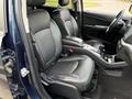 Interior view of a 2013 Dodge Journey with black leather seats and a central console showing cup holders and controls