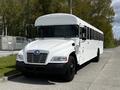 A 2022 Blue Bird BB Conventional school bus with a white exterior and large windows parked on a concrete surface
