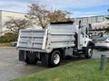 A 2011 International WorkStar truck with a gray dump bed parked on a surface with grass and asphalt