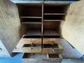 A wooden cabinet with multiple shelves and drawers, featuring labeled compartments for small tools and hardware, displaying a worn, rustic appearance