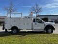 A white 2018 Ford F-550 with a utility body and equipment storage compartments on the side