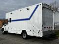 A white 2006 GMC C5000 truck with a blue stripe on the side and a large cargo area at the back