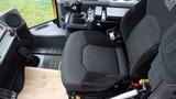 A black mesh seat of a 2019 Caterpillar 972M XE with armrests and controls nearby