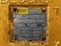 A metal identification plate mounted on a yellow surface displaying specifications such as model number weight and design factor