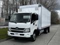 A 2018 Hino 195 truck with a white box cargo body parked on a street with a clean and modern design featuring a prominent front grille and large windshield