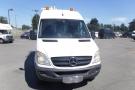 A 2012 Mercedes-Benz Sprinter van with a white exterior and orange hazard lights on the roof facing directly toward the viewer
