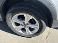 Close-up of the front tire and alloy wheel of a 2014 Ford Escape showing five spokes and the Ford logo on the hubcap