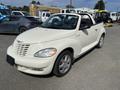 A white 2005 Chrysler PT Cruiser convertible positioned at an angle showcasing its front end and side profile with a black license plate area