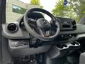 Interior view of a 2020 Mercedes-Benz Sprinter featuring a steering wheel dashboard and center console with controls and cup holders