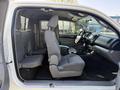 A 2015 Toyota Tacoma interior with two front seats and a rear bench seat all in gray fabric, featuring a simple dashboard and console design