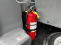 A red fire extinguisher secured in place inside a 2017 Ford Transit 350 with visible safety labels and a yellow inspection tag