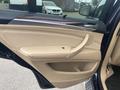 The interior door panel of a 2009 BMW X5 featuring beige leather upholstery and a silver trim with a control button and door handle