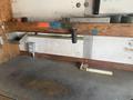 A wooden workbench with a metal ruler attached and a black rubber mallet resting on it