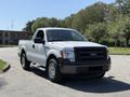 A white 2014 Ford F-150 pickup truck parked on a street with a single cab and chrome wheels