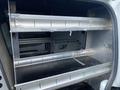 Interior of a 2013 Ford Transit Connect featuring metal shelving for storage with a flat surface and a minimalist design
