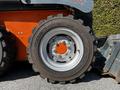 A close-up view of a tire from a 2017 Gehl R105 with a rugged tread pattern and a gray rim featuring an orange hub